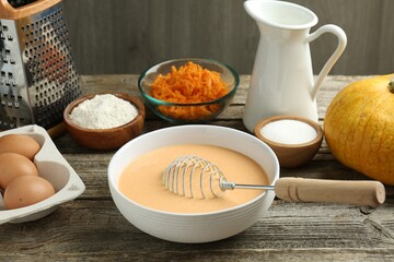 Bowl with dough and ingredients for pumpkin pancakes on wooden table