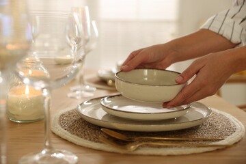 Woman setting table for dinner at home, closeup