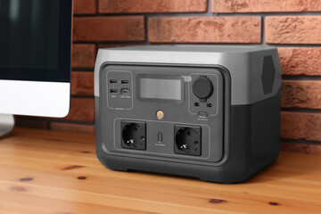 Obraz premium Portable power station on wooden desk near brick wall