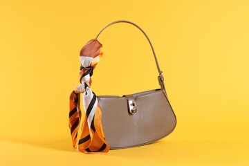 Stylish brown leather bag with handkerchief on yellow background