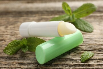 Natural lip balm and mint leaves on wooden background, closeup