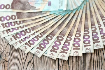 Big amount of ukrainian new one hundred hryvnia money bills with modern design on wooden background. Financial concept, business