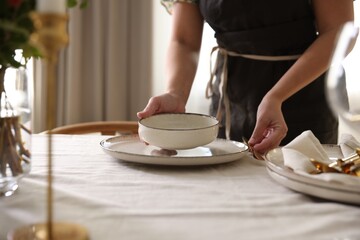 Woman setting table for dinner at home, closeup