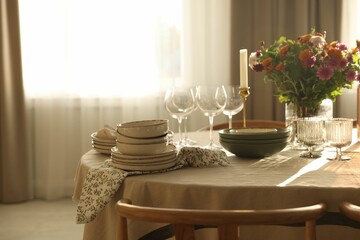 Stylish table setting with dishware, glasses and beautiful flowers indoors