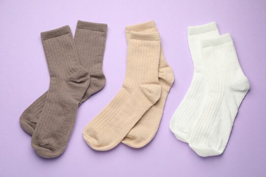 Different soft socks on violet background, flat lay