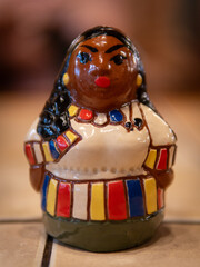 A beautifully crafted figurine showcasing a woman in colorful traditional dress, with intricate details and bright colors, sits on a countertop, highlighting artisanal skill.