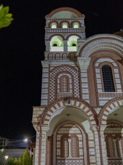 Obraz premium A stunning church with intricate brickwork and colorful designs stands tall against the night sky. Illuminated windows highlight its historical significance and craftsmanship.