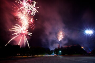 Massive, red, smoky fireworks in night sky near stadium