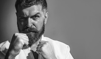 Bearded man training karate at gym. Karate man with clenched fists looks focused and confident....