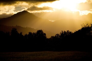 Silhouette of forest and mountains of Hawaii with sun beams peeking through clouds