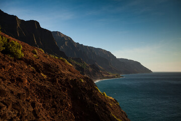 Sunset glow on beautiful Hawaiian island cliffs and ocean, wide shot