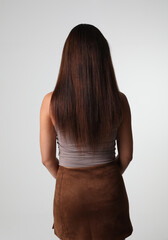 Naklejka premium Portrait of a beautiful and shy woman with luxurious long hair. Back view.