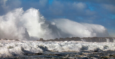 Ocean wave crashing over rocky island patch