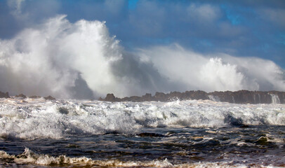 Crashing, foaming ocean waves on rocky patch near island 