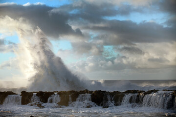 Silhouette of beautiful crashing ocean wave and rocky island platform