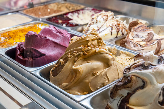Variety of gourmet artisan craft organic gelato ice cream flavors in a shop cafe display case, creamy textures with caramel nuts chocolate, berry sorbet, colorful ice cream selection, dessert shop