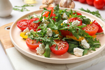 Tasty salad with arugula, cheese and vegetables on white table, closeup