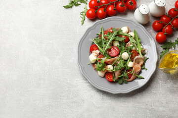 Tasty salad with arugula on grey textured table, flat lay. Space for text