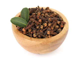 Dry clove buds and green leaves in wooden bowl on white background. Aromatic spice