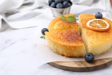 Tasty semolina cake served on white marble table, closeup. Space for text