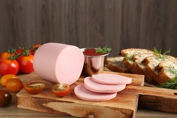 Tasty boiled sausage, ketchup, tomatoes, dill and bread on wooden table, closeup