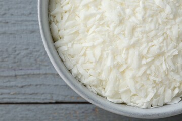 Soy wax in bowl on grey wooden table, top view