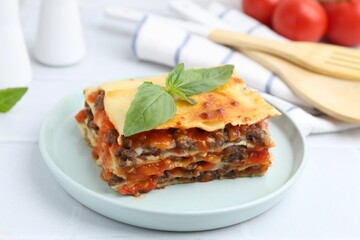 Delicious cooked lasagna with basil on white table, closeup