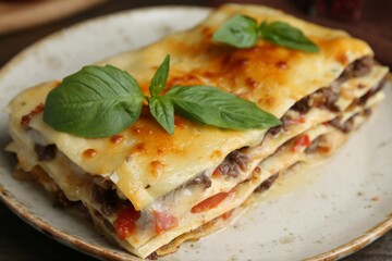 Delicious cooked lasagna with basil on plate, closeup