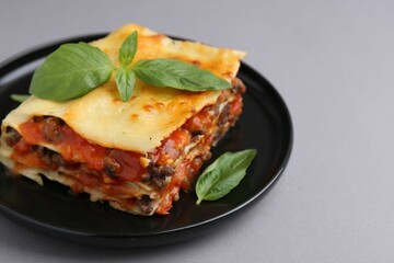 Delicious cooked lasagna with basil on grey table, closeup. Space for text