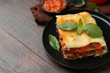 Delicious cooked lasagna with basil on wooden table, closeup. Space for text