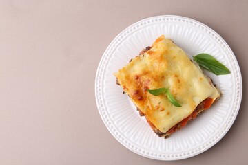 Delicious cooked lasagna with basil on light grey table, top view. Space for text