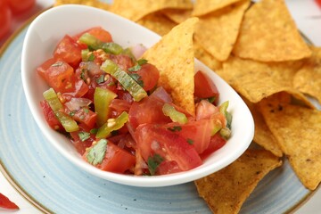 Delicious salsa (Pico de gallo) served with nachos on table, closeup