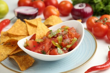 Delicious salsa (Pico de gallo) served with nachos and products on white table, closeup