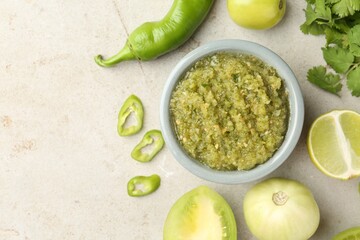 Delicious salsa sauce in bowl and ingredients on light textured table, flat lay. Space for text