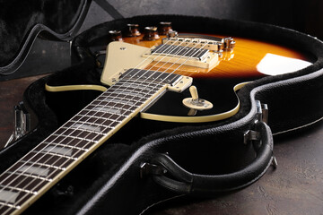 Old electric guitar against the background of a red concrete wall.