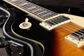 Old electric guitar against the background of a red concrete wall.