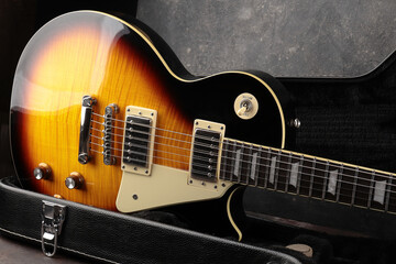 Old electric guitar against the background of a red concrete wall.
