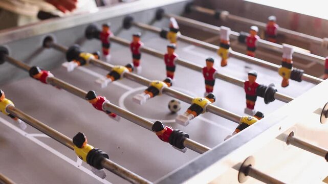 Group of friends playing kicker in a sports bar room, colleagues teammates play table football, table soccer game in the office, having fun, tabletop football match competition at work 