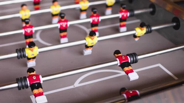 Group of friends playing kicker in a sports bar room, colleagues teammates play table football, table soccer game in the office, having fun, tabletop football match competition at work 