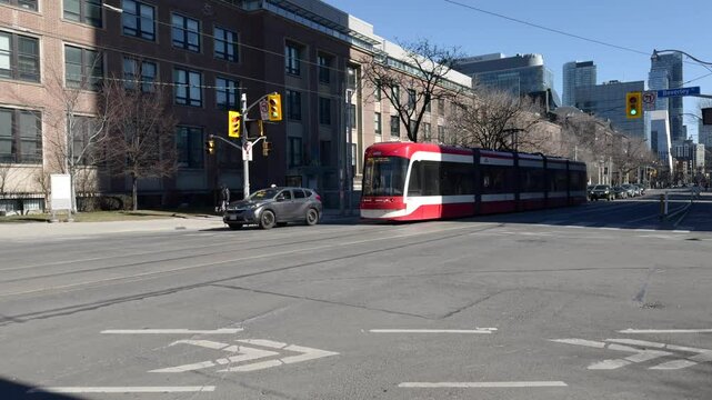 Toronto, Ontario, City tram speeds up along the street at sunny, spring day.