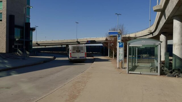 Slow motion, a bus leaves a bus stop on a sunny winter day.