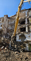 Demolition of building. Excavator breaks old house. long armed demolition machine seen demolishing a building.