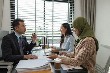 group of businessmen are discussing in an office. businessmen of different culture are meeting to make products that are appropriate and religiously correct. A businesswoman is wearing a hijab.