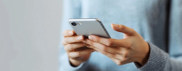 Closeup of hands using mobile phone young man texting on smartphone over light grey background