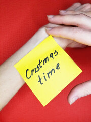 christmas time yellow sticker on female hand on red background
