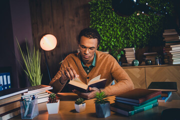 Young student studying at home with books and plants, focused on learning, indoors in the evening under warm natural light.