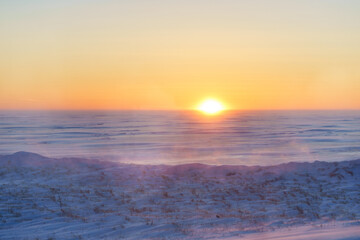 Sun setting over a wind swept frozen harbour.