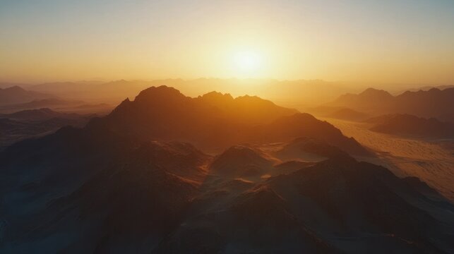 Golden sunset over a desert landscape with distant mountain ranges.