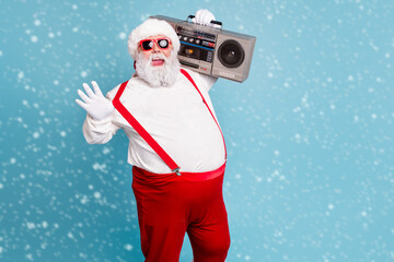 Portrait of nice bearded cheerful funky funny glad big belly Santa carrying tape player having fun isolated over bright vivid shine vibrant blue turquoise color background © deagreez