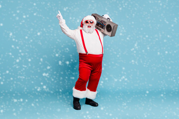 Full length body size view of his he nice cool bearded cheerful cheery Santa carrying vintage cassette player dancing having fun isolated on bright vivid shine vibrant blue turquoise color background © deagreez